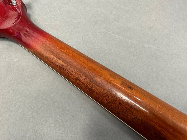 Close-up of vintage guitar neck showing wood grain and finish wear on a reddish-brown acoustic guitar neck at Coffee House Guitars
