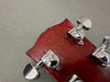 Close-up of red guitar headstock with chrome Grover tuning pegs and serial number 184812 stamped, showing "Made in Japan" text on the back