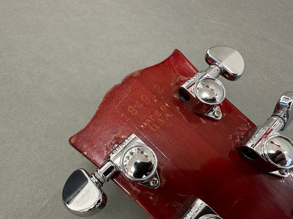 Close-up of red guitar headstock with chrome Grover tuning pegs and serial number 184812 stamped, showing "Made in Japan" text on the back