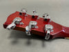 Back view of red guitar headstock showing six chrome tuning pegs on gray background