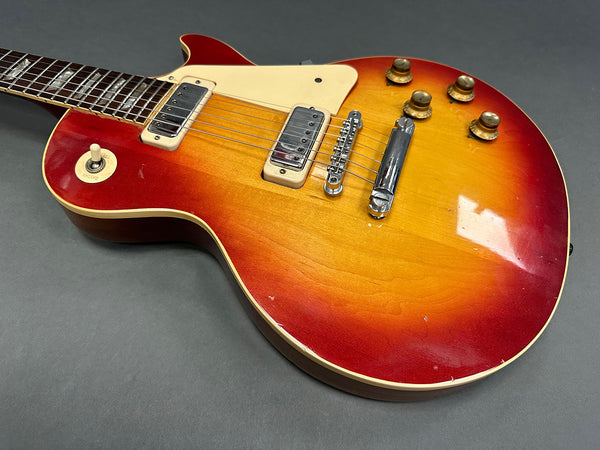 Vintage sunburst electric guitar with cream pickguard and chrome bridge on gray background