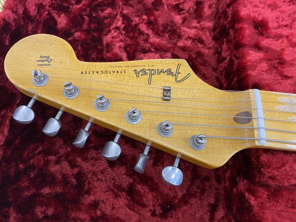 Close-up of vintage Fender Stratocaster electric guitar headstock with original tuning pegs on red plush background