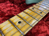 Close-up of worn maple guitar neck with metal frets and black dot inlays on red plush guitar case interior