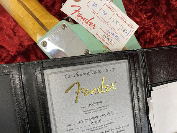 Fender Certificate of Authenticity for 1957 Stratocaster Heavy Relic guitar with serial number R101238 and Fender hang tag on guitar neck showing serial number and part number on red plush case background.