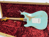 Fender Custom Shop vintage relic light blue electric guitar with distressed finish lying in red velvet lined hard case showing back of the body and neck with natural maple wood and chrome tuning pegs