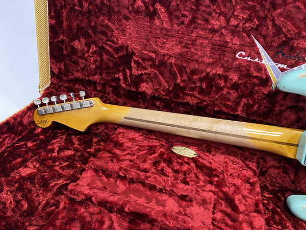 Back of Fender Custom Shop electric guitar neck with vintage tuners resting in red plush guitar case labeled Fender Custom Shop