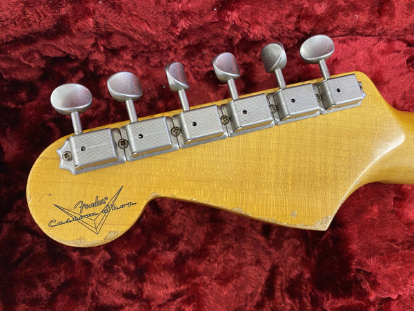 Vintage Fender Custom Shop guitar headstock with six tuning pegs and worn natural wood finish on red plush background