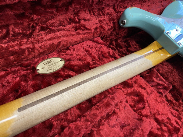 Vintage electric guitar neck with maple wood and a darker wood stripe, shown resting on plush red guitar case interior with a G&G "The Original Vintage Case Co." metal plaque, made in USA 2019