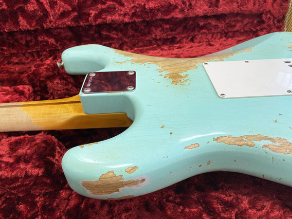 Close-up of vintage relic worn light blue electric guitar body with neck joint and chrome neck plate on red plush guitar case interior