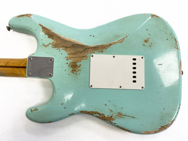 Back of relic light blue electric guitar body with worn paint and wood patches, white plastic backplate, and bolt-on maple neck with skunk stripe