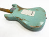 Back view of light blue relic finish electric guitar with worn paint and white backplate on a wood neck against white background