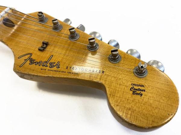 Close-up of vintage Fender Stratocaster guitar headstock with worn original contour body finish and metal tuning pegs