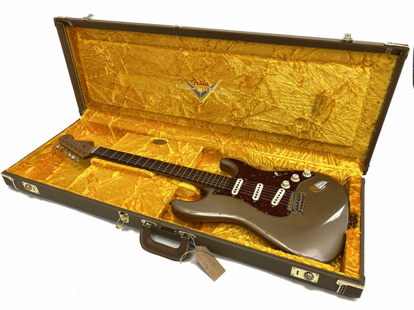 Vintage Fender Stratocaster electric guitar in metallic finish with tortoiseshell pickguard, displayed inside original yellow velvet-lined Fender hard case