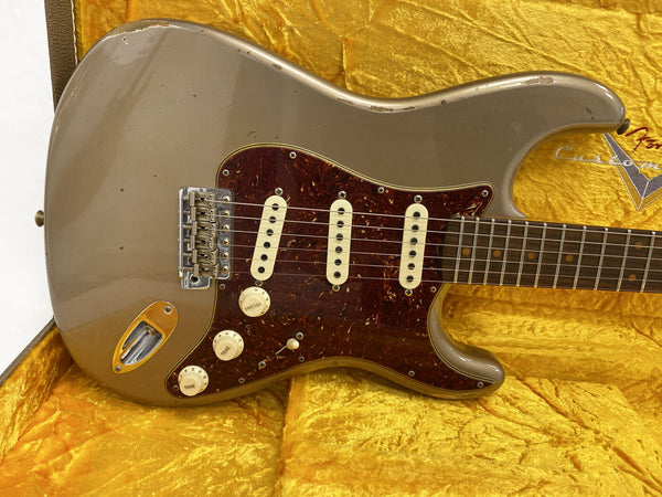 Vintage Fender Stratocaster electric guitar with worn gray finish, tortoiseshell pickguard, three single-coil pickups, and white control knobs in yellow-lined hard case