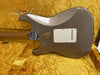 Back of worn Fender Custom Shop electric guitar with beige finish and white plastic tremolo cover in yellow plush-lined guitar case