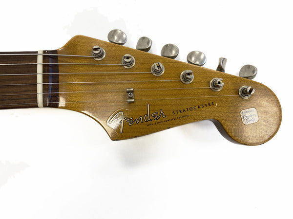 Close-up of vintage Fender Stratocaster guitar headstock with six tuning pegs and original guitar badge on white background
