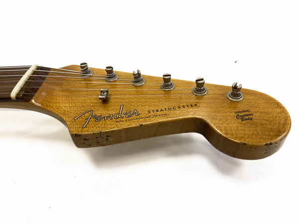 Close-up of vintage Fender Stratocaster guitar headstock with six tuning pegs and worn original contour body finish on white background