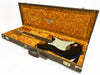 Vintage Fender Stratocaster electric guitar with black finish and white pickguard inside a brown Fender Custom Shop hard case lined with orange plush interior