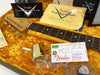 Fender Stratocaster guitar neck and headstock with tuning pegs, Fender Custom Shop cleaning cloth and certificate, gold guitar tremolo arm, and Fender inspection tag inside orange plush guitar case lining.