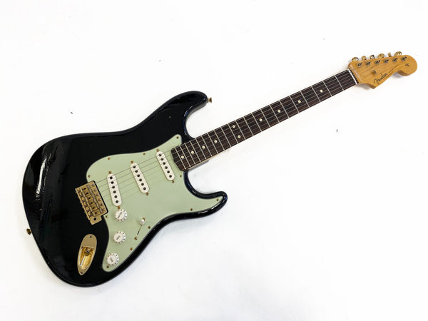 Black Fender Stratocaster electric guitar with mint green pickguard and rosewood fingerboard, vintage style single-coil pickups and maple neck
