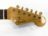 Close-up of Fender Stratocaster guitar headstock with vintage tuning pegs and strings, natural wood finish and black Fender logo, original contour body text visible