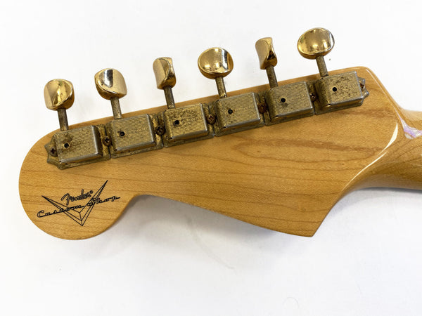 Close-up image of vintage Fender Custom Shop guitar headstock with six aged gold tuning pegs on natural wood finish