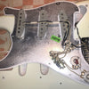 Close-up of vintage style guitar pickguard with three single-coil pickups and wired electronic components for electric guitar assembly