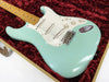Seafoam green electric guitar with maple neck and white pickguard in red plush-lined guitar case