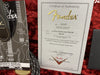 Fender Certificate of Authenticity for 55 Strat Journeyman Relic guitar with serial number R87781, accompanied by Fender owner's manual and guitar cable on red plush background.