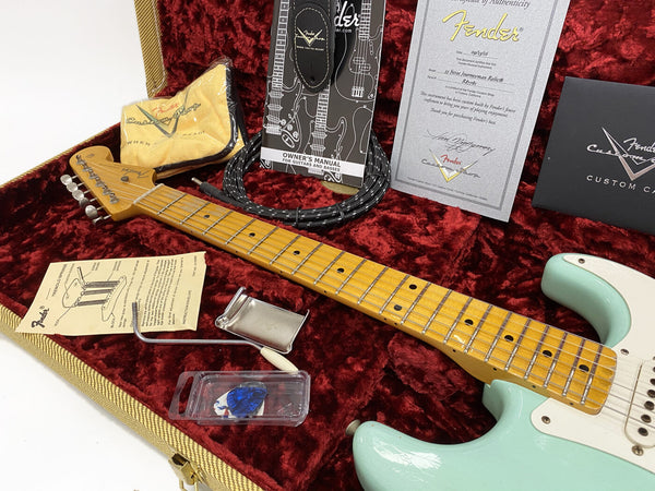 Fender Stratocaster electric guitar neck and body in surf green finish displayed in a red velvet-lined guitar case with Fender Custom Shop certificate of authenticity, owner's manual, tremolo springs, guitar pick, and strap.