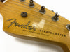 Close-up of Fender Stratocaster guitar headstock with vintage tuning pegs and synchronized tremolo system logo on natural wood finish