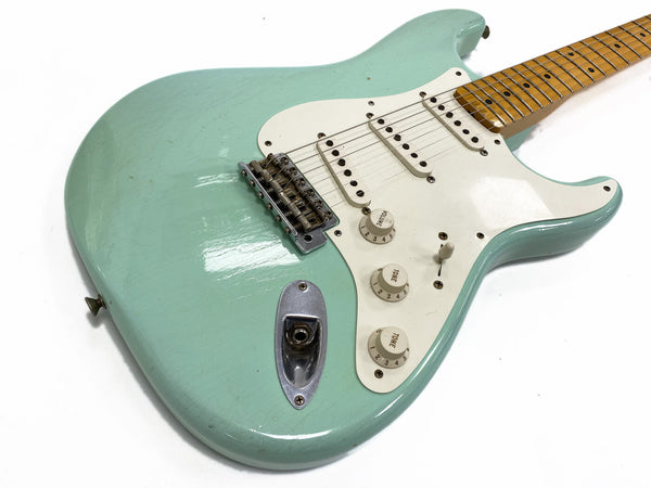 Light blue vintage electric guitar with white pickguard and maple neck, close-up of body and controls on white background