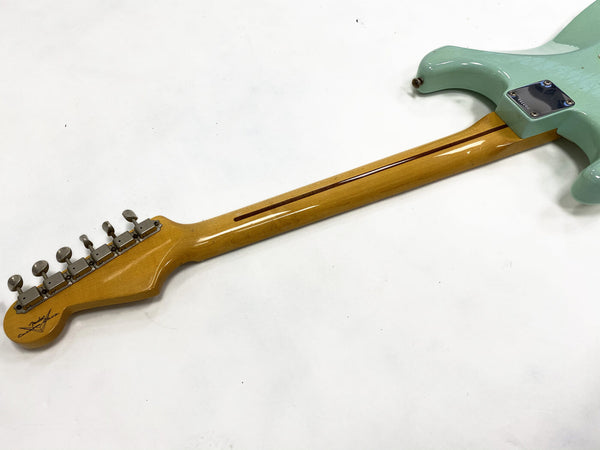 Close-up of Fender Custom Shop electric guitar neck, maple fretboard with skunk stripe, and seafoam green body on white background