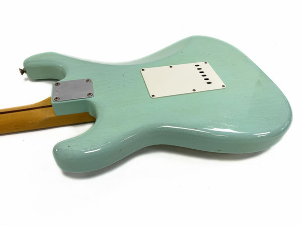Back view of seafoam green electric guitar body with white plastic backplate and maple neck with skunk stripe on white background