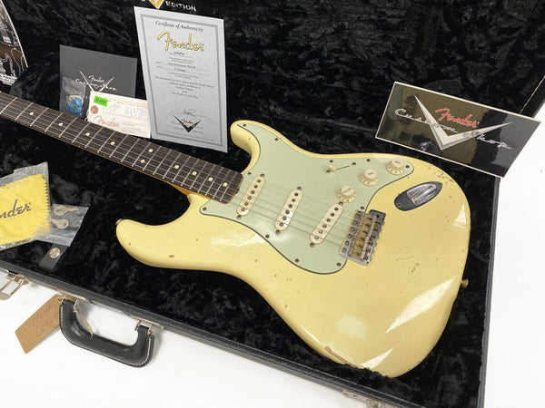 Fender Custom Shop 1954 Stratocaster Relic electric guitar in vintage white with worn finish, rosewood fretboard, three single-coil pickups, and vintage-style tremolo, displayed in black plush-lined hard case with certificate of authenticity and Fender Custom Shop accessories.