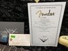 Fender Custom Shop Certificate of Authenticity for 1964 Stratocaster Relic Limited Edition guitar with serial number CZ509595, Fender Custom Shop tag, guitar pick, and guitar neck on black plush background