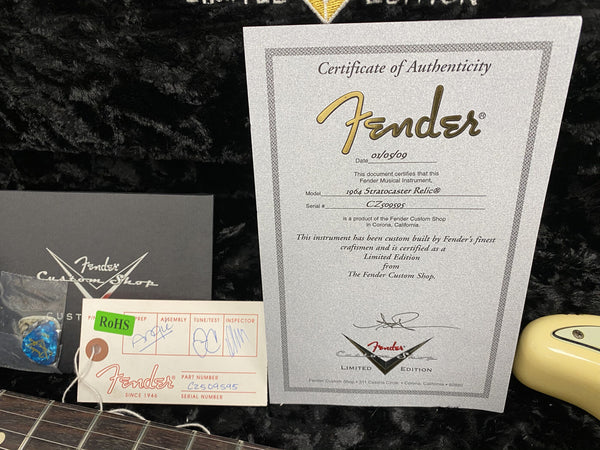 Fender Custom Shop Certificate of Authenticity for 1964 Stratocaster Relic Limited Edition guitar with serial number CZ509595, Fender Custom Shop tag, guitar pick, and guitar neck on black plush background