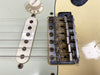 Close-up of vintage Fender Stratocaster electric guitar bridge, single coil pickup, volume knob, and strings on aged cream finish body.