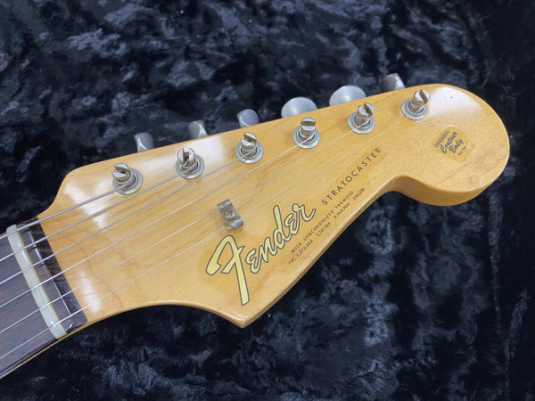 Close-up of Fender Stratocaster guitar headstock with vintage original tuning pegs and logo on a black textured background