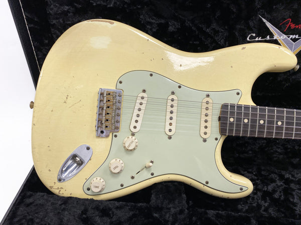 Vintage cream Fender Stratocaster electric guitar with three single-coil pickups and mint green pickguard showing natural wear and aging in black guitar case