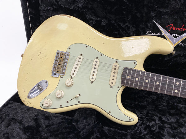 Vintage cream Fender Stratocaster electric guitar with aged wear and three single-coil pickups on black plush case interior