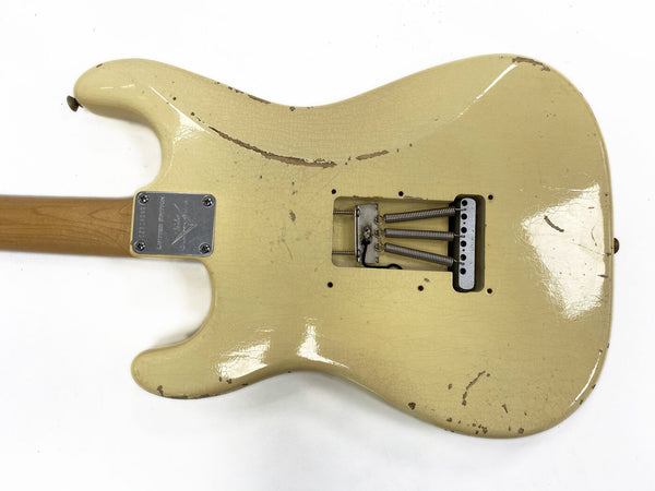 Vintage cream electric guitar body with visible wear and tremolo springs, maple neck, metal neck plate with serial number, shown from back side on white background