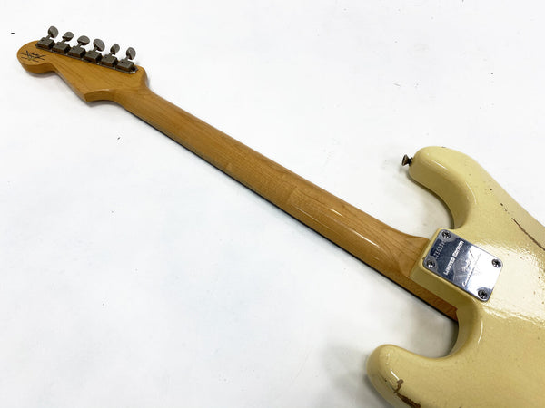Back view of vintage Fender Stratocaster electric guitar neck and body with maple fretboard and cream finish showing neck plate and tuning pegs