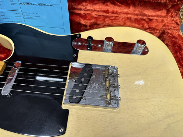 Close-up of vintage Fender Telecaster guitar bridge and control plate with knurled knobs on blonde body in red plush case