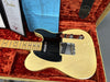 Fender Telecaster electric guitar with maple neck and vintage blonde finish resting in a reddish-orange plush lined hardshell case, accompanied by Fender certificate and specification sheet.