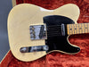 Vintage cream Fender Telecaster electric guitar close-up with black pickguard and chrome hardware in plush red case interior