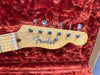 Close-up of Fender electric guitar maple headstock with tuning pegs on red plush guitar case lining
