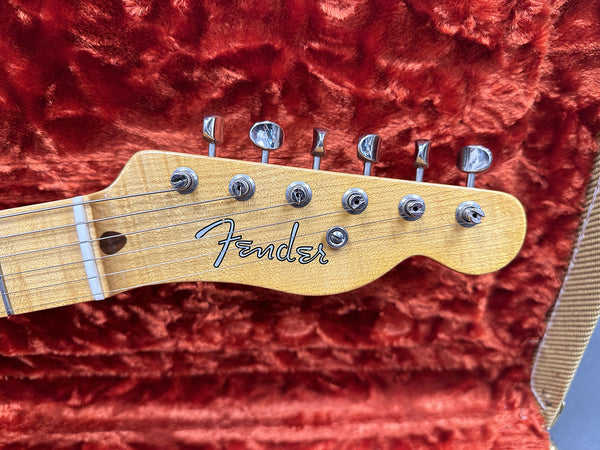 Close-up of Fender electric guitar maple headstock with tuning pegs on red plush guitar case lining