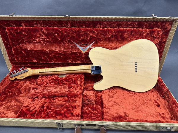 Back view of natural wood electric guitar with maple neck and chrome tuning pegs in red plush Fender Custom Shop case