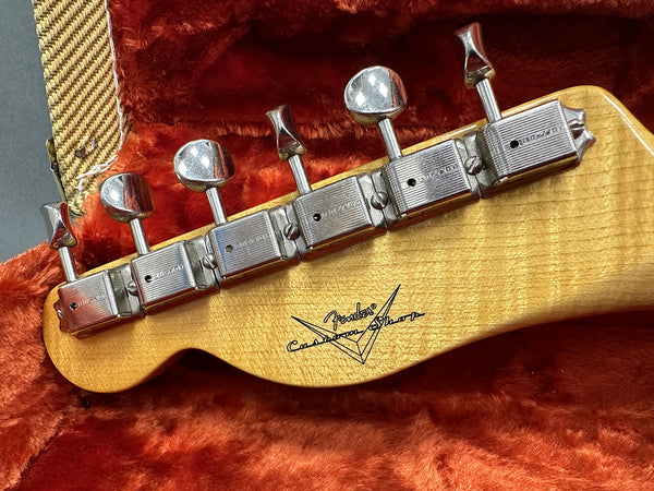 Close-up of vintage Fender Custom Shop guitar headstock with six chrome tuning pegs in a red plush-lined case